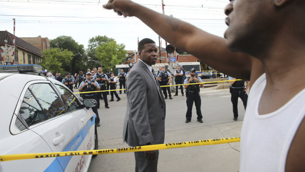 Members of the Chicago Police Department look at an angry crowd gathered at the scene of a police involved shooting in Chicago, on Saturday.