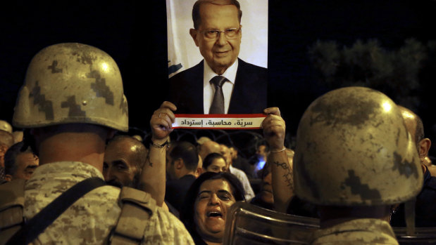 A supporter of Lebanese President Michel Aoun holds up his picture during a protest near the presidential palace in Beirut on Tuesday.