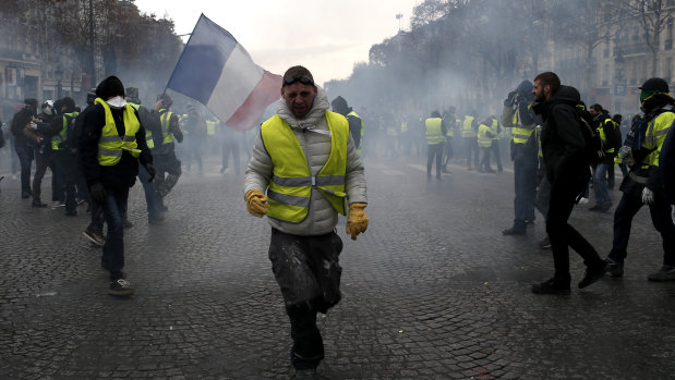 A demonstrator wearing a yellow vest grimaces through tear gas.