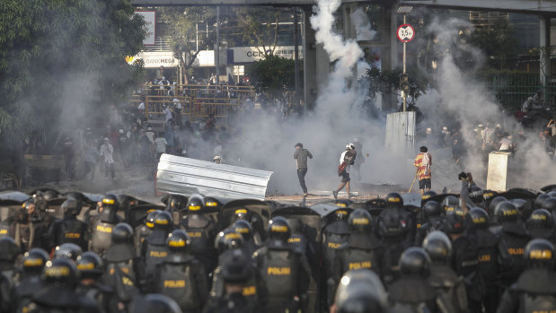 Indonesian riot police officers fire a tear gas launcher to disperse supporters of Indonesian presidential candidate Prabowo Subianto.