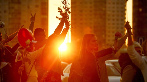 People wave flowers as they gather to protest against the results of the country's presidential election during sunset in Minsk, Belarus.