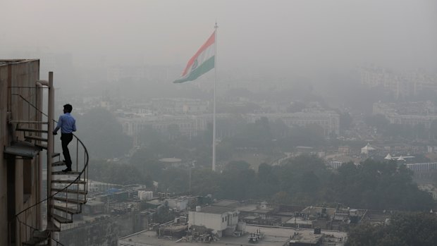 A man climbs to the top of a Delhi building as the city is enveloped in smog and dust on Friday.