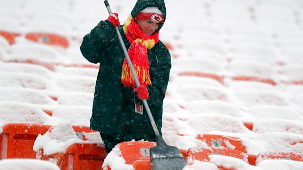 A groundskeeper brushes snow off seats at Arrowhead Stadium before an NFL divisional football playoff game  in Kansas City on  Saturday.