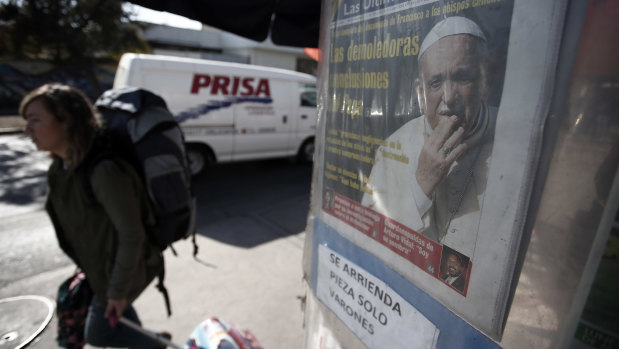 A pedestrian walks past a newspaper stand featuring an image of Pope Francis, in Santiago, Chile.