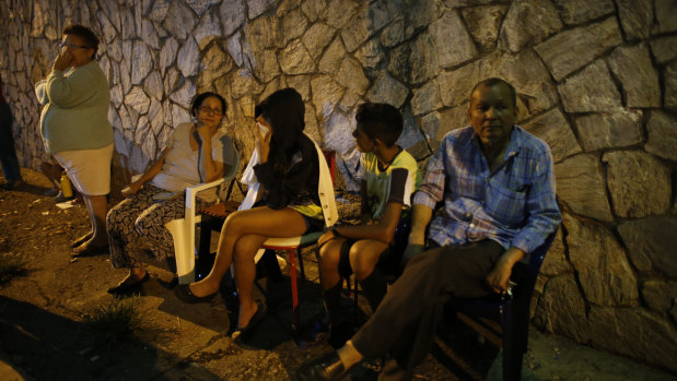 Evacuated residents sit outside their apartments in a street near the leaning tower.