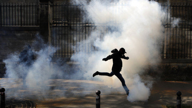 An activist kicks a tear canister gas shot by riot police during a Paris protest in support of the French railway employees.