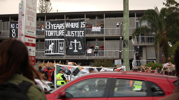 Protesters join below as some men protest on the Kangaroo Point hotel balcony in August.