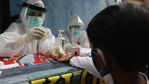 A boy waits to receive a coronavirus antibody test from health workers at a village in Bali, Indonesia.