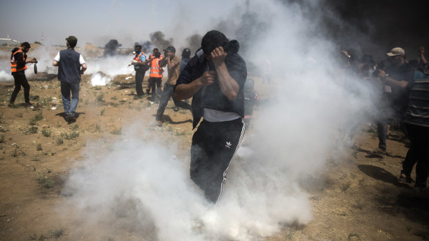 Palestinian protesters run for cover from teargas fired by Israeli troops during fresh demenstrations in which medics said four people died. 