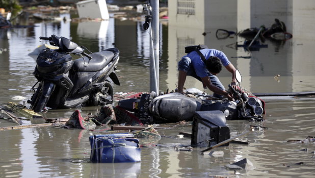 A man tries to get his motorbike upright at a tsunami-devastated area in Talise beach, Palu.