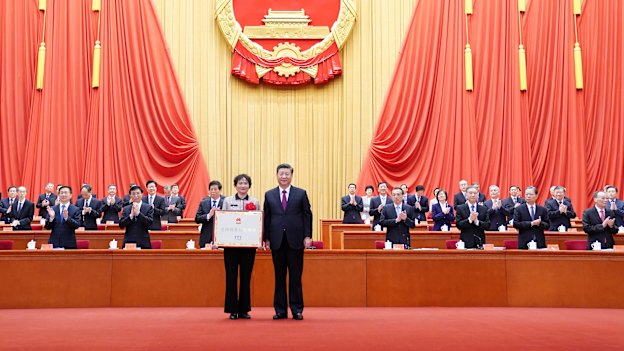 Xi Jinping presents an award to a village in Anhui province for being a role model in fighting poverty, in Beijing in February 2021.