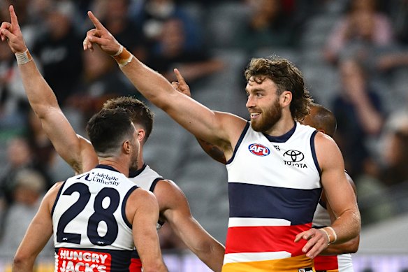 Riley Thilthorpe of the Crows is congratulated by team mates after kicking a goal.