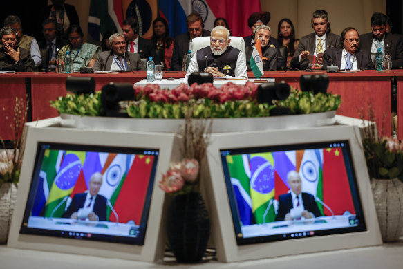 India’s Prime Minister Narendra Modi, centre, looks on at the plenary session as Russian President Vladimir Putin delivers his remarks via video link, at the 2023 BRICS Summit in Johannesburg.