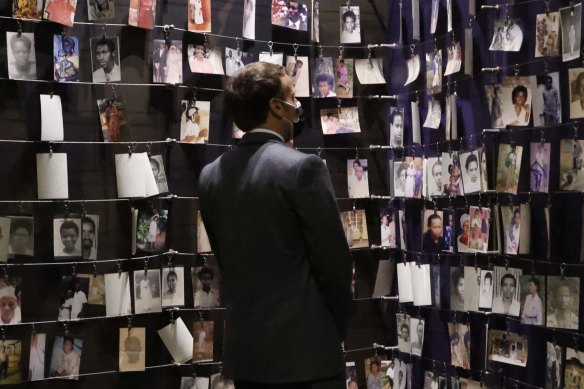 French President Emmanuel Macron looks at the images of genocide victims on display during his visit to the Kigali Genocide Memorial, where some 250,000 victims of the Rwanda massacres are buried, in Kigali.