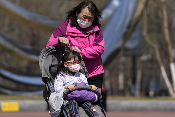 A woman wearing a face mask to help protect from the coronavirus brings a masked child visit to a park, in Beijing on Sunday.