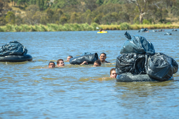 Manly players swim their gear across a dam in central NSW.