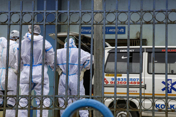 Health workers in protective suits wait outside the emergency ward of a hospital after bringing a suspected coronavirus patient in an ambulance in Kolkata, India.