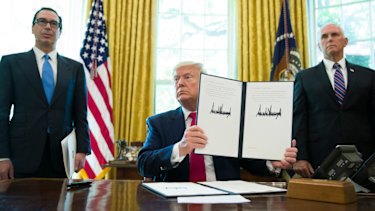 President Donald Trump holds up a signed executive order to increase sanctions on Iran.