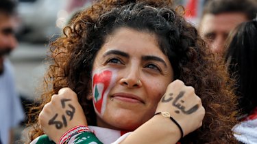 An anti-government protester displays the words "Revolution" left, and "Lebanon" right, in Arabic on her hands.