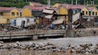 Villagers gather near a Shidongzi village signboard on a bridge damaged by floods after heavy rains in Miyun district on the outskirts of Beijing. 