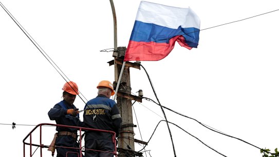 Municipal workers attach a Russian national flag to a pole preparing to celebrate 77 years of the victory in WWII in Mariupol,  Thursday, May 5, 2022. 