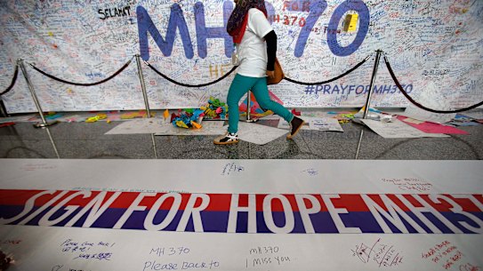 A woman walks past a banner filled with signatures and well-wishes for the missing Malaysia Airlines jetliner MH370 at the Kuala Lumpur International Airport in the days after the plane went missing.
