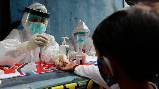 A boy waits to receive a coronavirus antibody test from health workers at a village in Bali, Indonesia, Wednesday, May 27, 2020. (AP Photo/Firdia Lisnawati)
