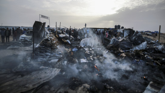 Palestinians look at the destruction after an Israeli strike where displaced people were staying in Rafah.