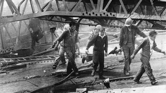 Westgate Bridge collapse, 1970: A victim is carried from a massive pile of twisted girders by civil defence men and workmates. 