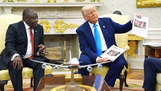 President Donald Trump shows documents as he meets South Africa’s President Cyril Ramaphosa in the Oval Office of the White House, Wednesday, May 21, 2025, in Washington. (AP Photo/Evan Vucci)