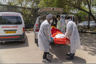 Voluntary health workers from the United Sikhs’ ambulance service remove the body of a COVID-19 victim from an ambulance at a crematorium in New Delhi.