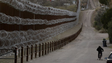 A boy rides his bike along a razor-wire-covered border wall that separates Nogales, Arizona, from Nogales, Mexico.