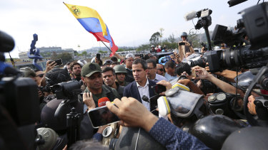Venezuela's opposition leader Juan Guaido, centre, stands with an unidentified military officer who looks to be helping to lead a military uprising.