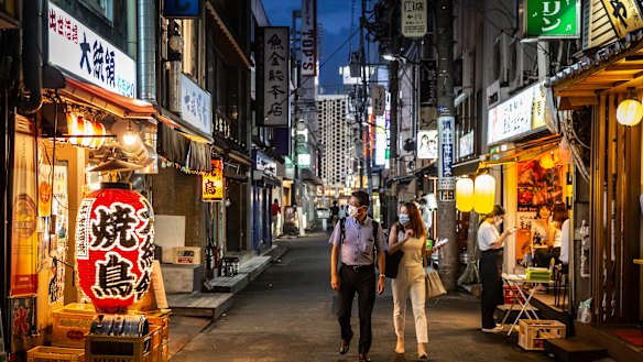People wearing face masks look into a bar  in Tokyo. 