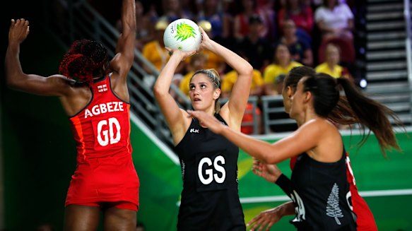 Te Paea Selby-Rickett of New Zealand, centre, and Ama Agbeze of England, left, compete during the preliminary round netball game.