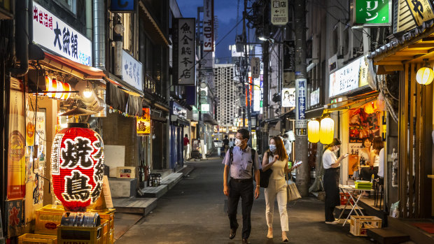 People wearing face masks look into a bar  in Tokyo. 