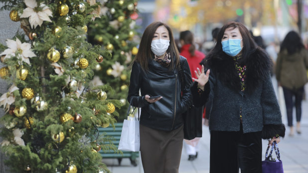 Shoppers wear face masks to help curb the spread of the coronavirus in the Ginza shopping district in Tokyo today.