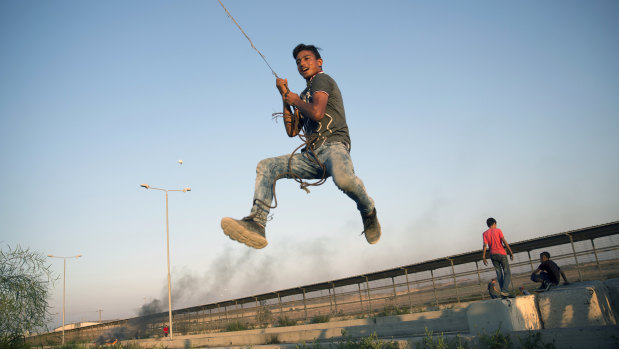 A Palestinian protester swings from a hanging metal cable during a protest at the entrance of Erez border crossing between Gaza and Israel, in the northern Gaza Strip last week.