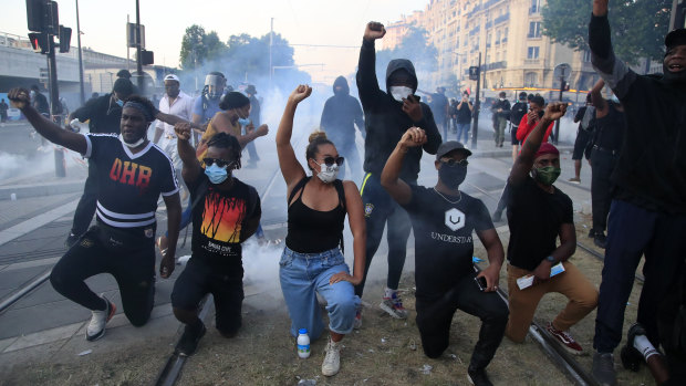 Protesters kneel in concert with US demonstrators in Paris on Tuesday. 