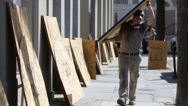 Preston Guiher carries a sheet of plywood as he prepares to board up a Wells Fargo bank location in preparation for Hurricane Florence in downtown Charleston, SC.