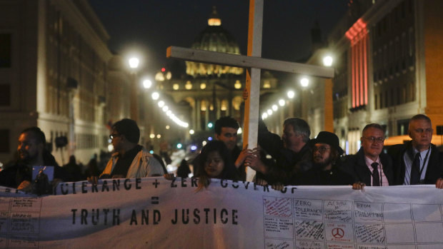 Survivors of sex abuse hold a cross on Via della Conciliazione, the road leading to St Peter's Square, during a twilight vigil for victims of sex abuse.