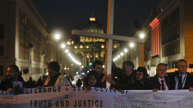 Survivors of sex abuse hold a cross on Via della Conciliazione, the road leading to St Peter's Square, during a twilight vigil for victims of sex abuse.