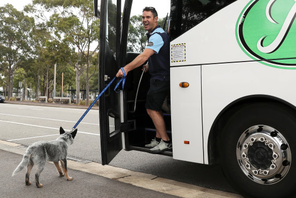 Fittler laughs as he tries to take Blues mascot Bruce the Blue Heeler puppy on the team bus.