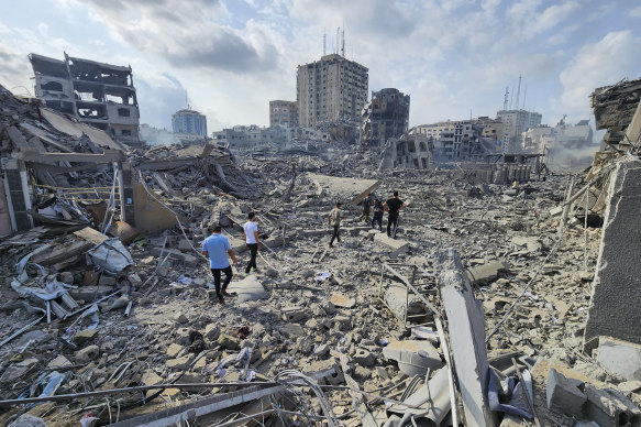 Palestinians walk through the rubble of buildings destroyed in Gaza City.