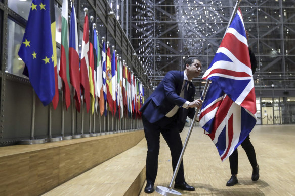 A member of protocol removes the Union flag from the atrium of the Europa building in Brussels on January 31, 2020. 