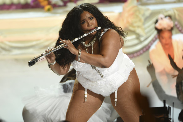 Lizzo playing her regular flute at a performance.
