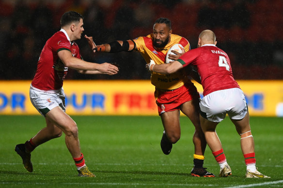 Justin Olam of PNG is tackled by Will Evans and Rhodri Lloyd of Wales during last month’s RLWC Pool D match.