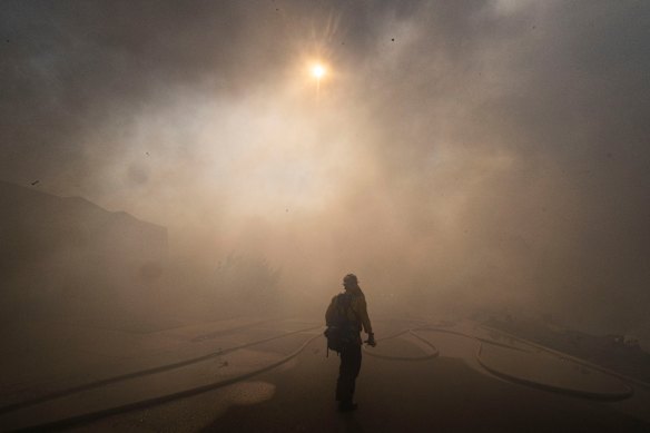 The sun is obscured by smoke as firefighters work to save structures in San Clemente, California.