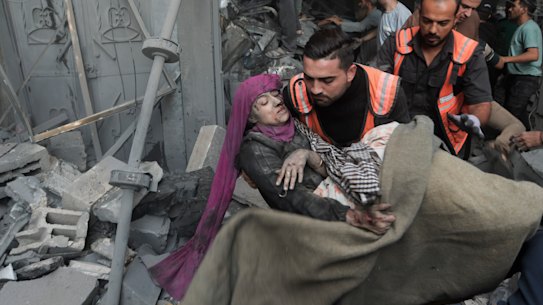 Palestinian rescuers evacuate an injured woman that was found under the rubble of a destroyed house following an Israeli airstrike in Khan Younis refugee camp,.