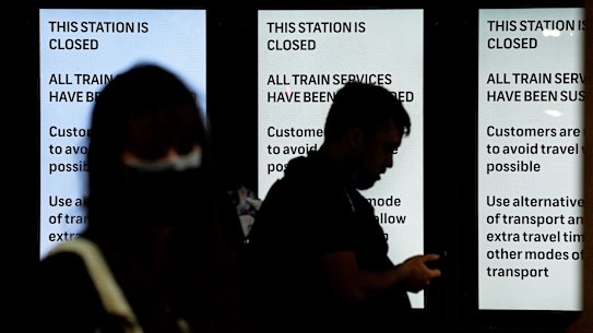 Commuters at the entrance to Central Station stand in front of notices stating the station is closed and all train services have been suspended after all Sydney Trains and Trainlink services were stopped due to industrial action. 21st February, 2022. Photo: Kate Geraghty 